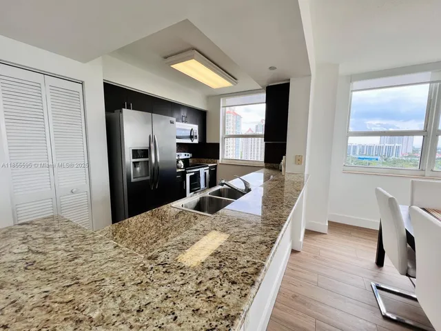 a large kitchen with kitchen island granite countertop a refrigerator stove microwave and sink