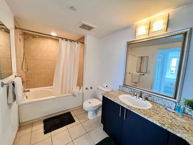 a bathroom with a granite countertop sink mirror toilet and bathtub