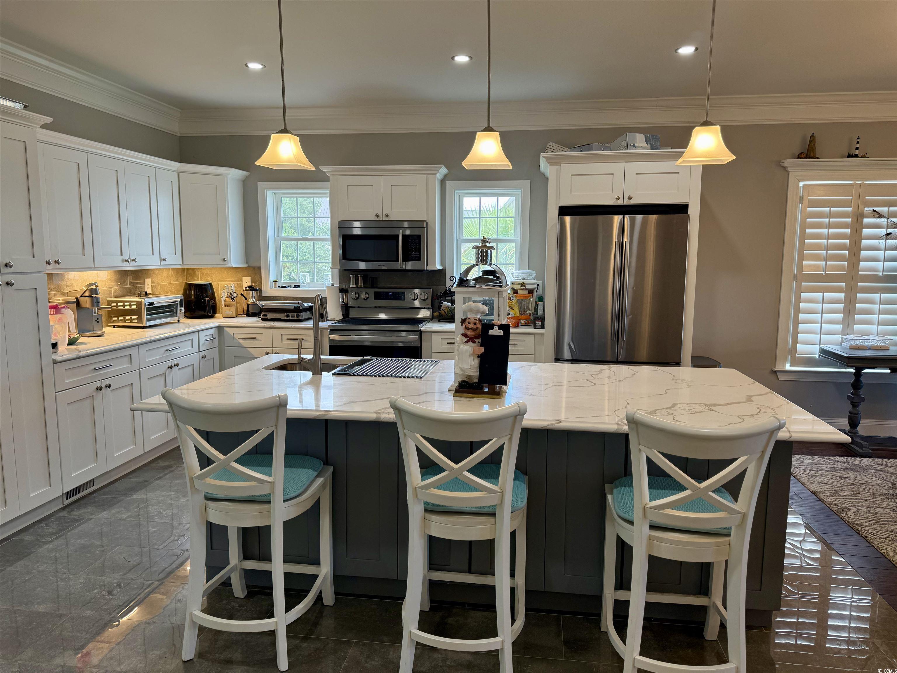 100 Oak Bay Drive Georgetown, SC 29440 - Photo 26 of 29 Kitchen featuring stainless steel appliances, an island with sink, white cabinets, crown molding, and a breakfast bar area