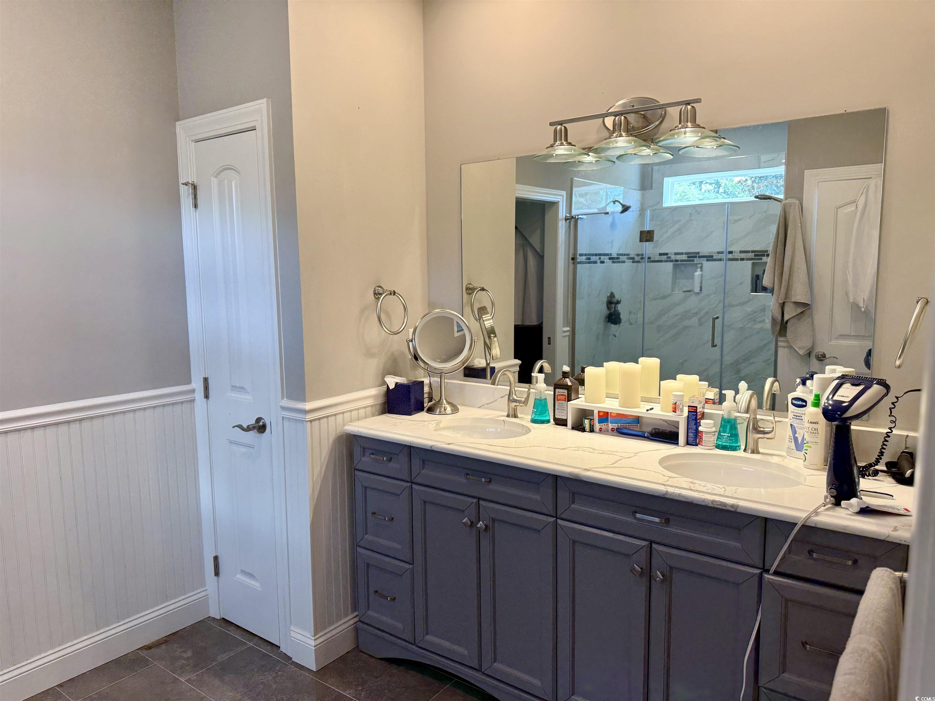 100 Oak Bay Drive Georgetown, SC 29440 - Photo 9 of 29 Bathroom featuring wainscoting, a shower stall, double vanity, and dark tile patterned flooring