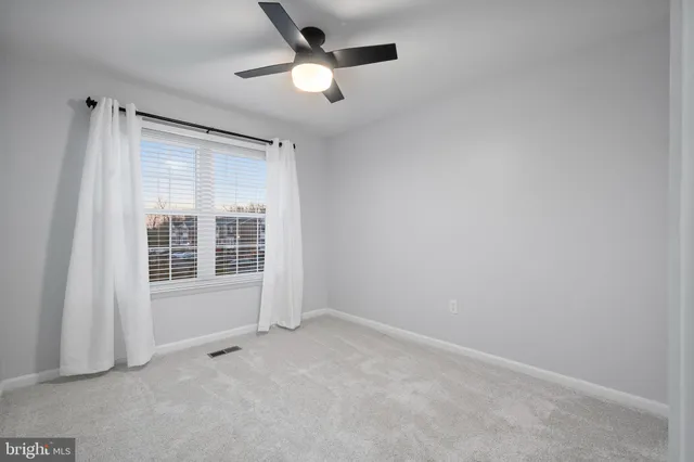 an empty room with a ceiling fan and windows
