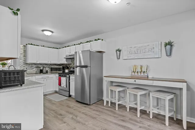 a kitchen with granite countertop a refrigerator and a stove top oven