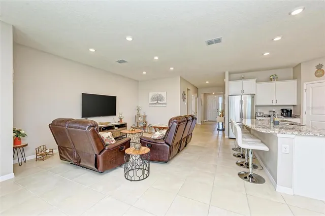 a living room with furniture a flat screen tv and kitchen view