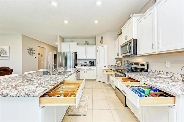 a living room with stainless steel appliances kitchen island granite countertop a sink dishwasher and a stove with wooden floor