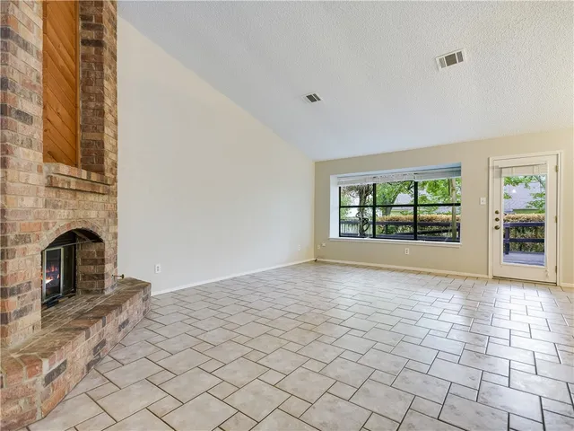 a view of empty room with fireplace and wooden floor
