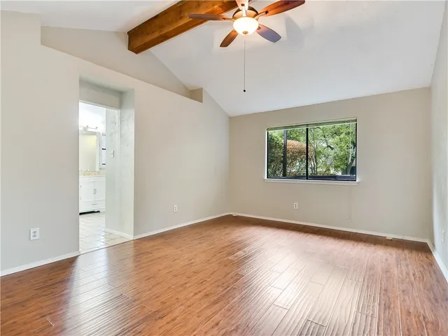 an empty room with wooden floor chandelier fan and windows