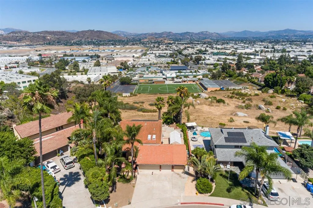 an aerial view of residential houses with outdoor space and trees