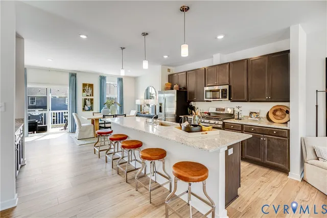 a open kitchen with stainless steel appliances granite countertop a stove refrigerator and a sink with wooden floor