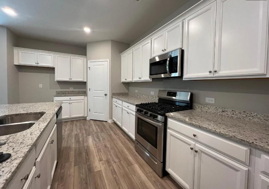 140 Golden Eagle Parkway Braselton, GA 30517 - Photo 2 of 13 a kitchen with granite countertop a sink dishwasher a stove and a microwave oven with cabinets