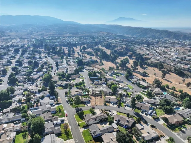 an aerial view of residential houses with outdoor space and trees