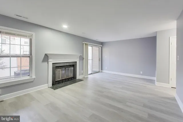an empty room with windows and fireplace