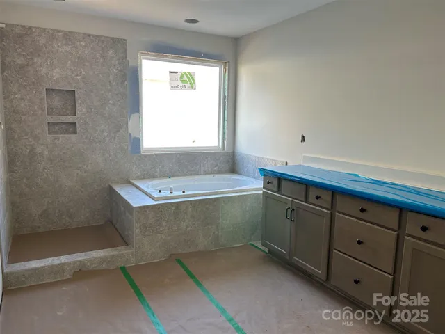 a spacious bathroom with double vanity a mirror a bathtub and a shower