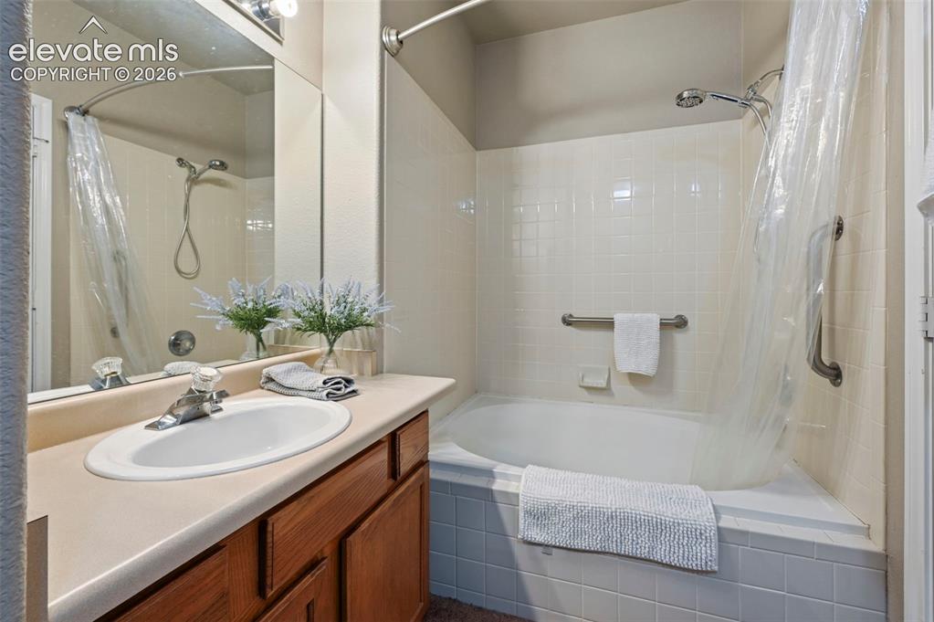 3715 Riviera Grove, Unit 101 Colorado Springs, CO 80922 - Photo 30 of 36 Bathroom featuring a vanity with an integrated sink, a large mirror, and a full-size bathtub with a shower