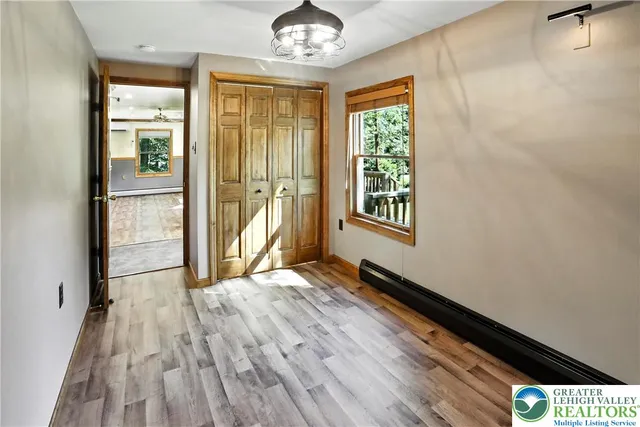 a view of an empty room with wooden floor and a window