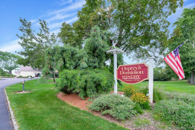 a sign that is sitting in the grass near a tree