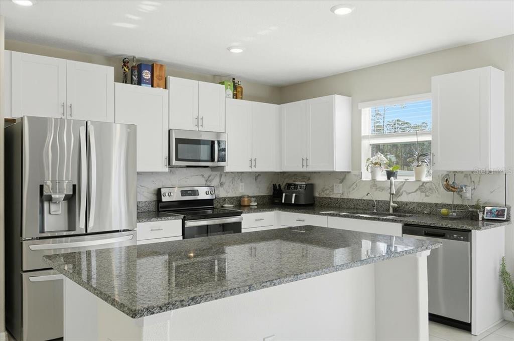 2175 Old Mining Road Lakeland, FL 33801 - Photo 7 of 51 a kitchen with granite countertop a sink a counter top space cabinets stainless steel appliances and a window