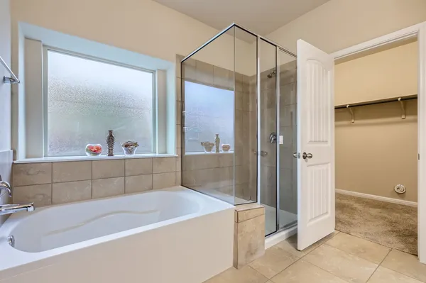 a bathroom with a tub a mirror and shower