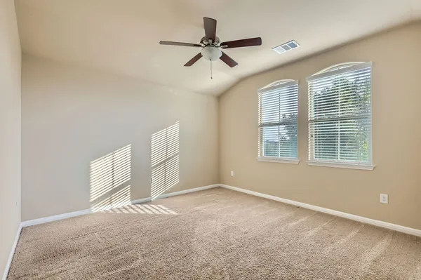 an empty room with windows and ceiling fan