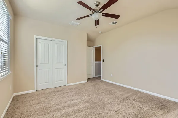 an empty room with a ceiling fan and carpet