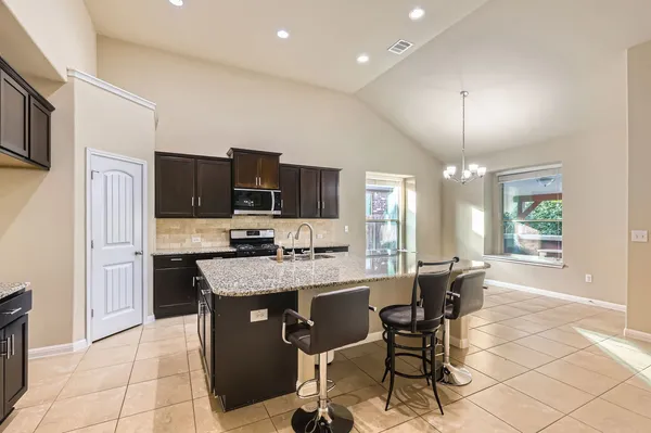a kitchen with stainless steel appliances granite countertop a stove top oven a sink dishwasher a dining table and chairs with wooden floor