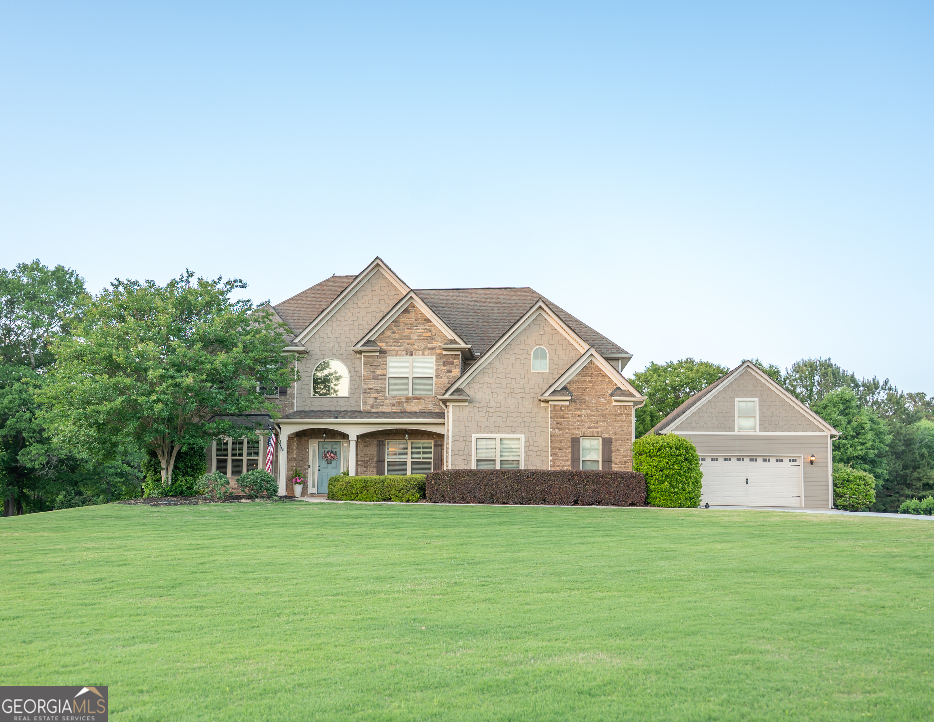a front view of a house with a yard and trees