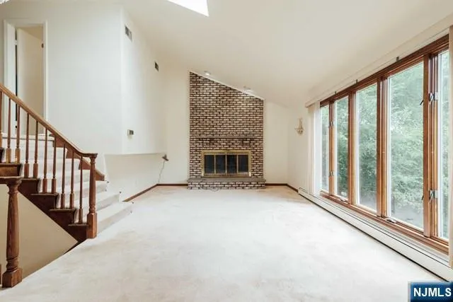 a view of an empty room with fireplace and a window