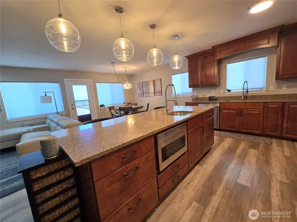 a open kitchen with stainless steel appliances granite countertop a stove a sink dishwasher and white cabinets with wooden floor