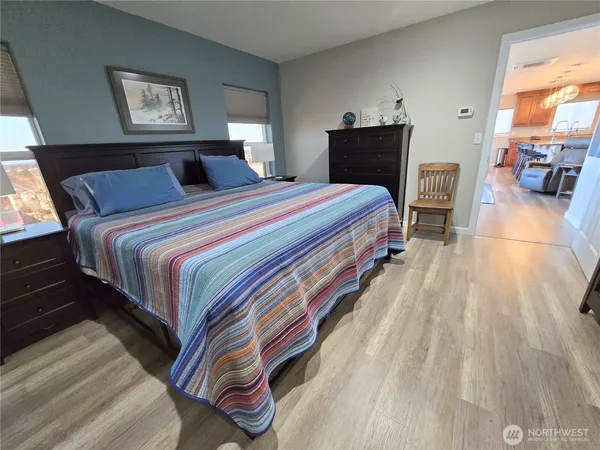 a bedroom with a bed and a lamp on dresser with a large window