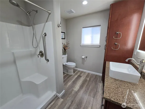 a bathroom with a granite countertop sink a toilet and shower