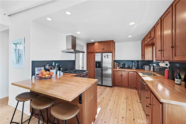 a kitchen with stainless steel appliances wooden floor dining table and chairs