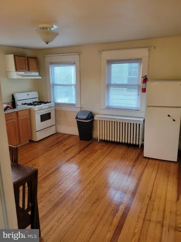 a kitchen with wooden floors and white stainless steel appliances