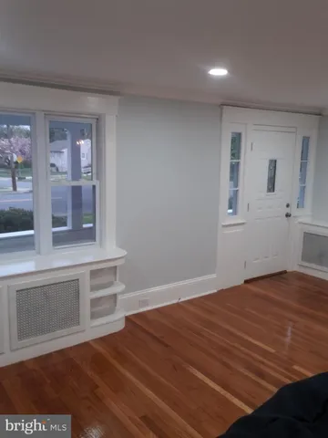 a view of an empty room with a window and wooden floor