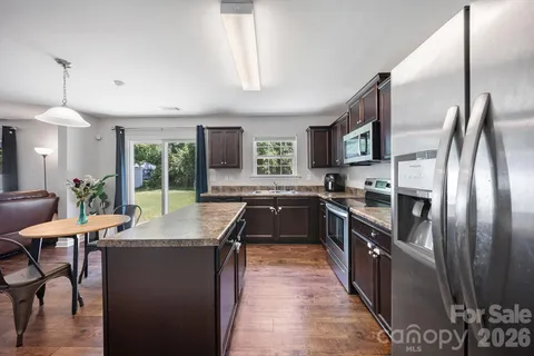 a kitchen with granite countertop a stove top oven a sink dishwasher and a refrigerator with wooden floor