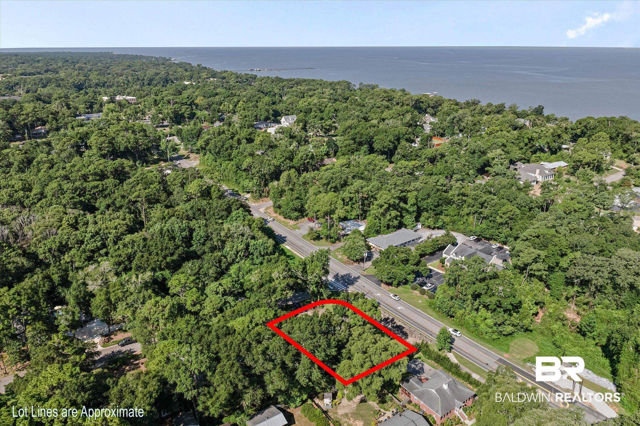 401 Frederick Avenue Fairhope, AL 36532 - Photo 26 of 36 Wooded lot outlined in red, featuring mature tree coverage, proximity to a paved road, and a distant body of water