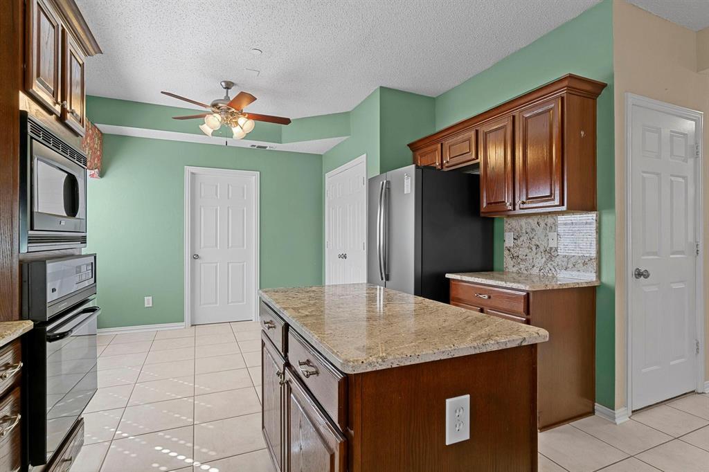 14588 Poe Court Addison, TX 75001 - Photo 15 of 28 a kitchen with a kitchen island a sink stainless steel appliances cabinets and furniture