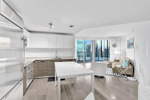 a living room with granite countertop furniture a rug kitchen view and large windows
