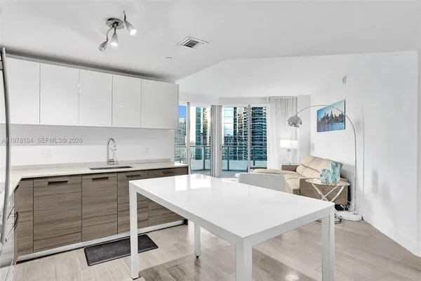 a kitchen with a stove a sink dishwasher and white cabinets with wooden floor