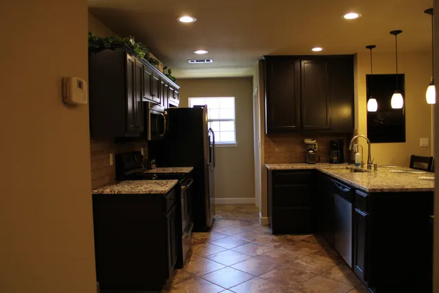 a kitchen with kitchen island granite countertop a sink counter top space appliances and cabinets