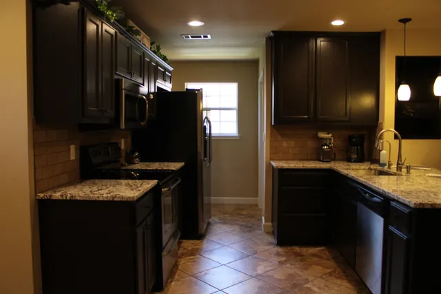 a kitchen with a granite countertop sink a stove a refrigerator and a microwave