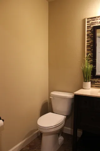 a bathroom with a toilet a sink and wooden floor