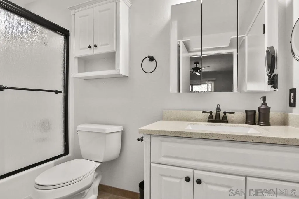 6359 Rancho Mission Road, Unit 7 San Diego, CA 92108 - Photo 17 of 25 a bathroom with a granite countertop toilet sink vanity and mirror