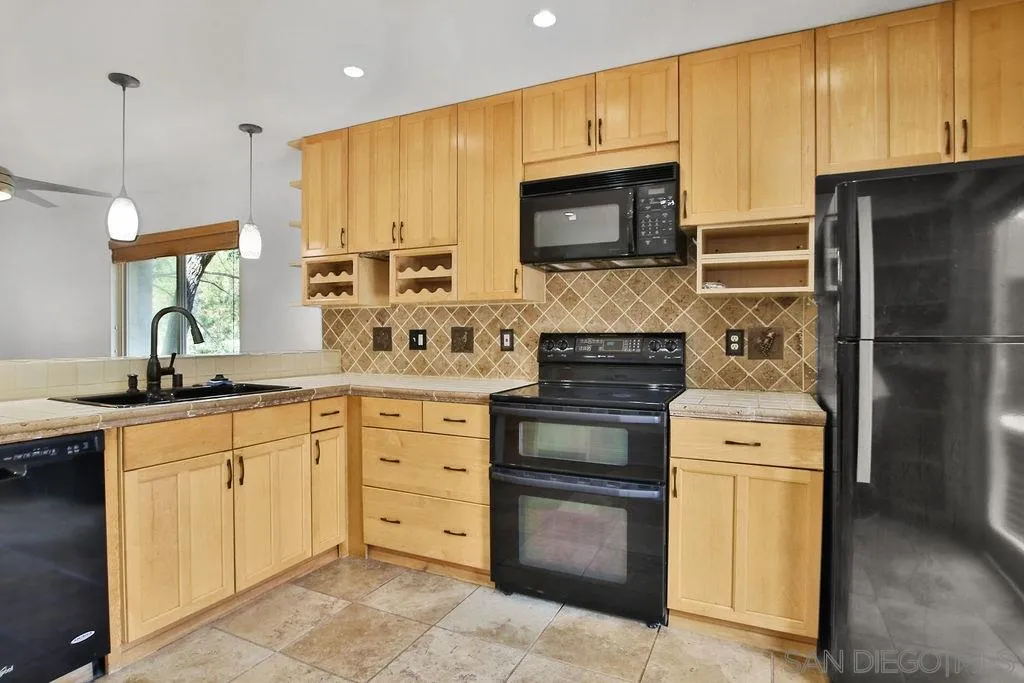 6359 Rancho Mission Road, Unit 7 San Diego, CA 92108 - Photo 6 of 25 a kitchen with stainless steel appliances granite countertop a stove a sink and a microwave