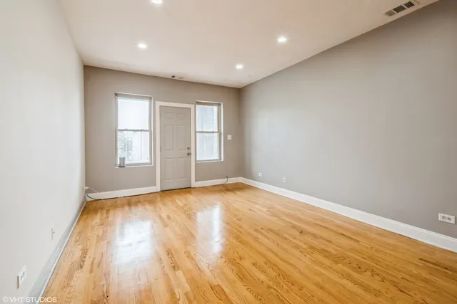 a view of empty room with wooden floor and fan