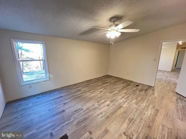 a view of an empty room with window and wooden floor