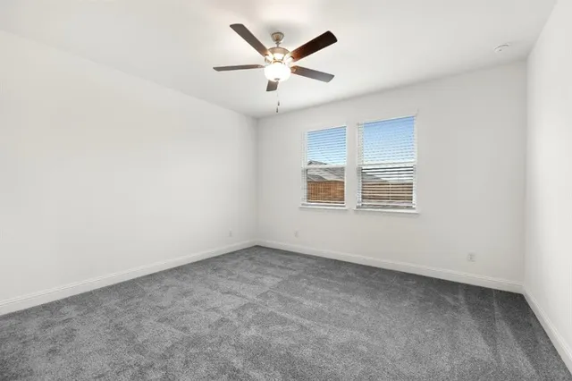 an empty room with windows and ceiling fan