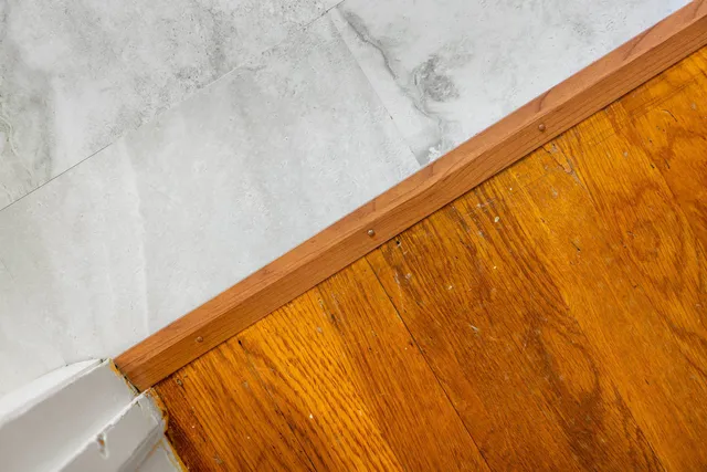 a view of an empty room with wooden floor and a ceiling fan