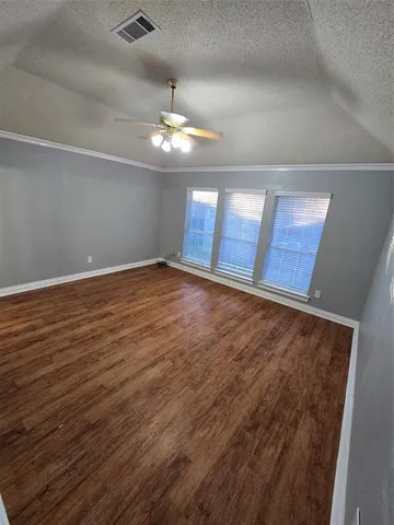 an empty room with wooden floor chandelier and windows