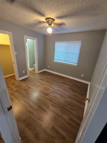 a view of an empty room with window and chandelier fan