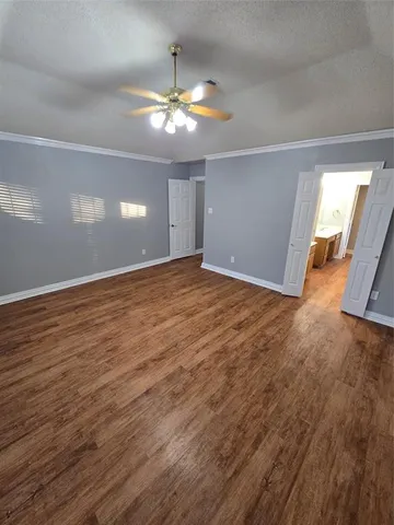 a view of an empty room with wooden floor and chandelier