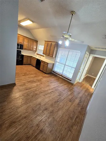 a large room with kitchen view and wooden floor